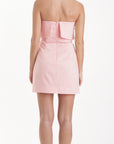 Woman wearing a pink strapless dress on a white background