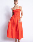 Woman wearing a bright orange dress against a white background
