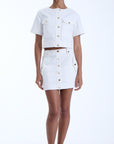 Woman wearing a white outfit with gold buttons on a white background