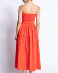 Woman wearing a red dress with thin straps on a white background