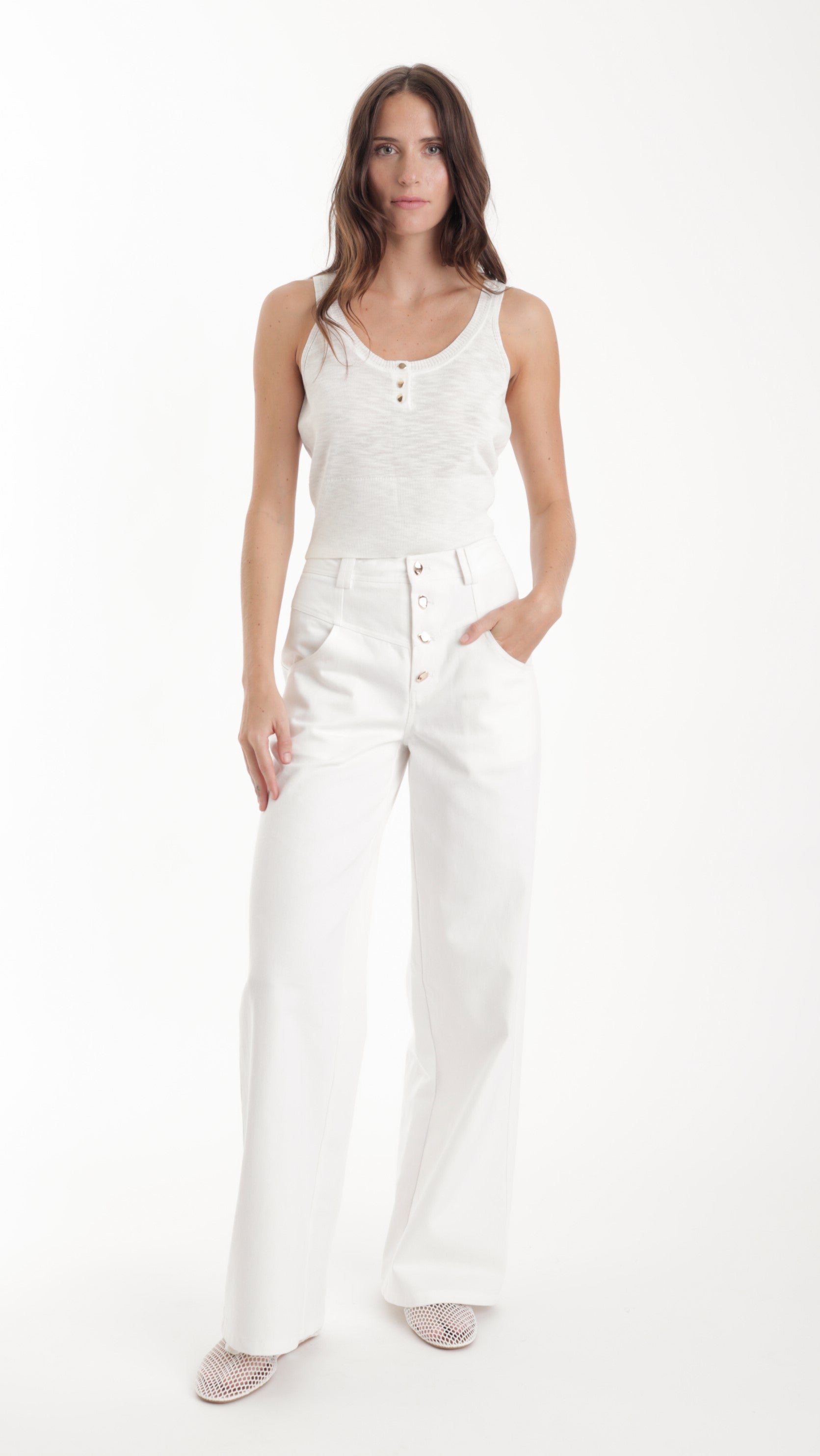 Woman wearing a white sleeveless top and pants on a white background