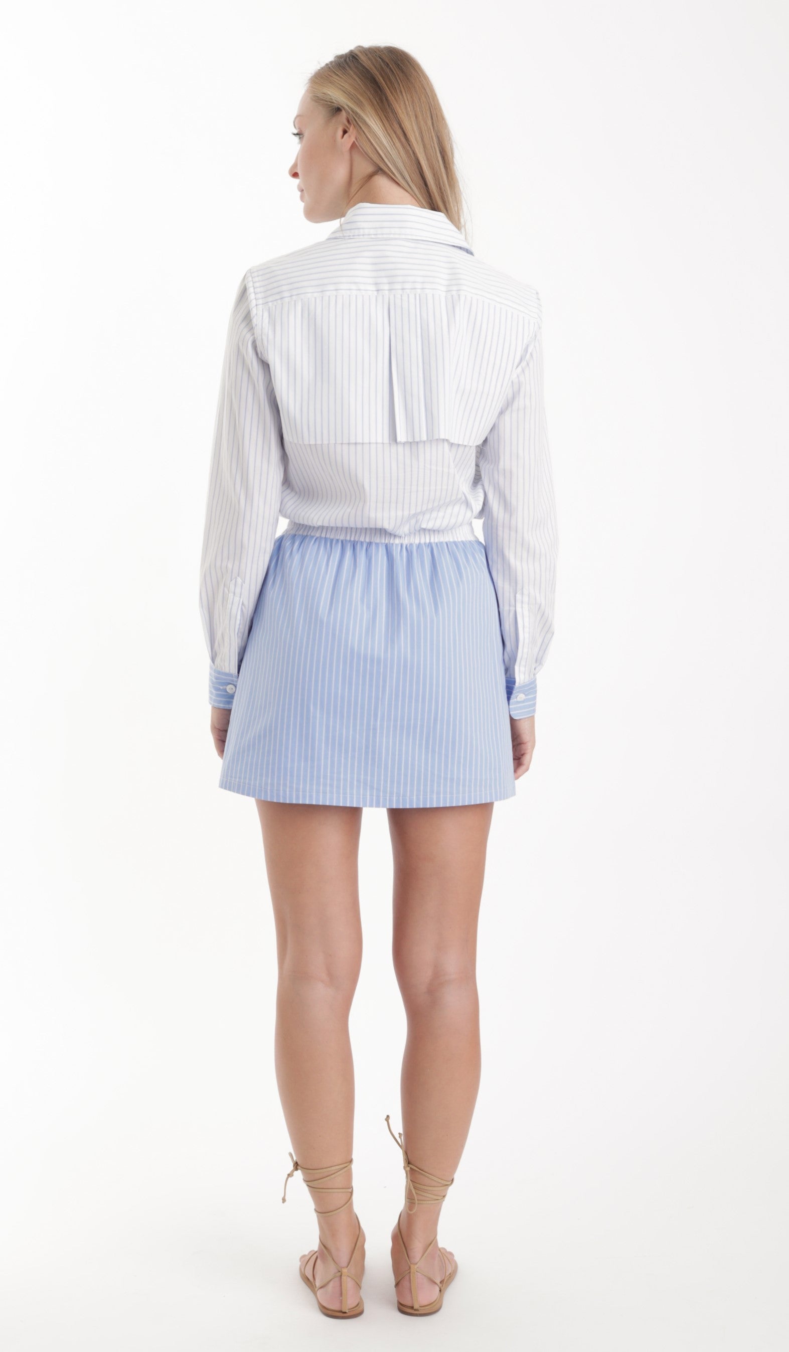 Woman wearing a white shirt and light blue striped skirt on a white background