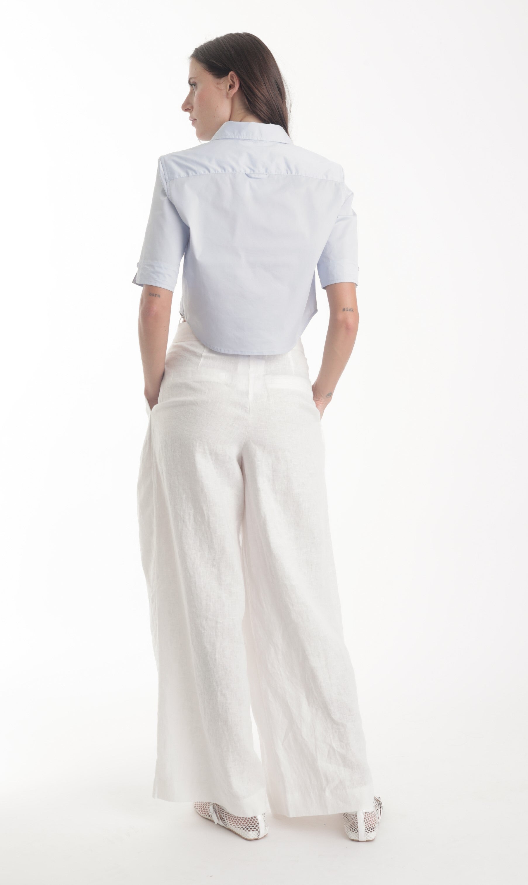 Woman wearing a light blue shirt and white pants on a white background
