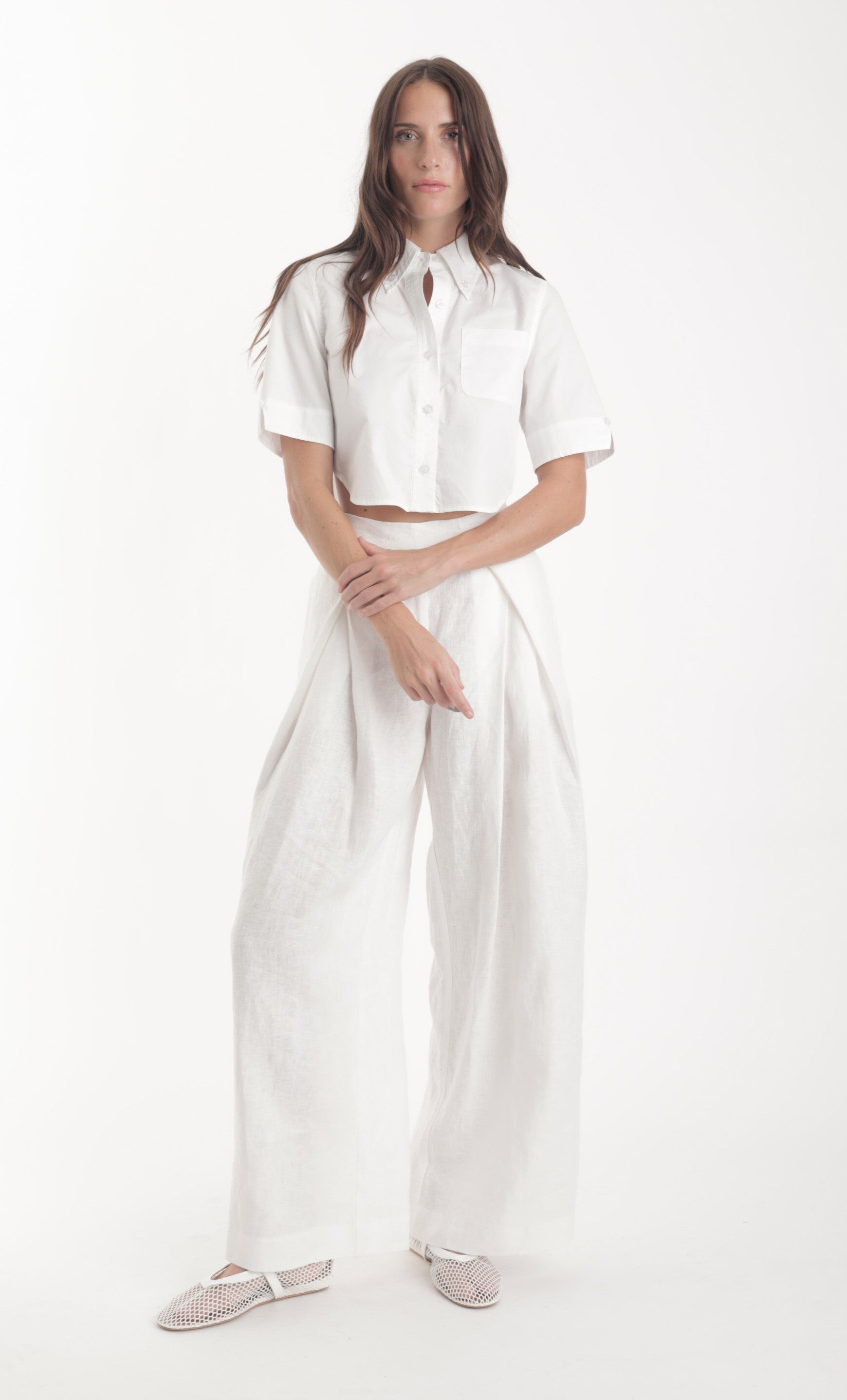 Woman wearing a light blue shirt and white pants on a white background
