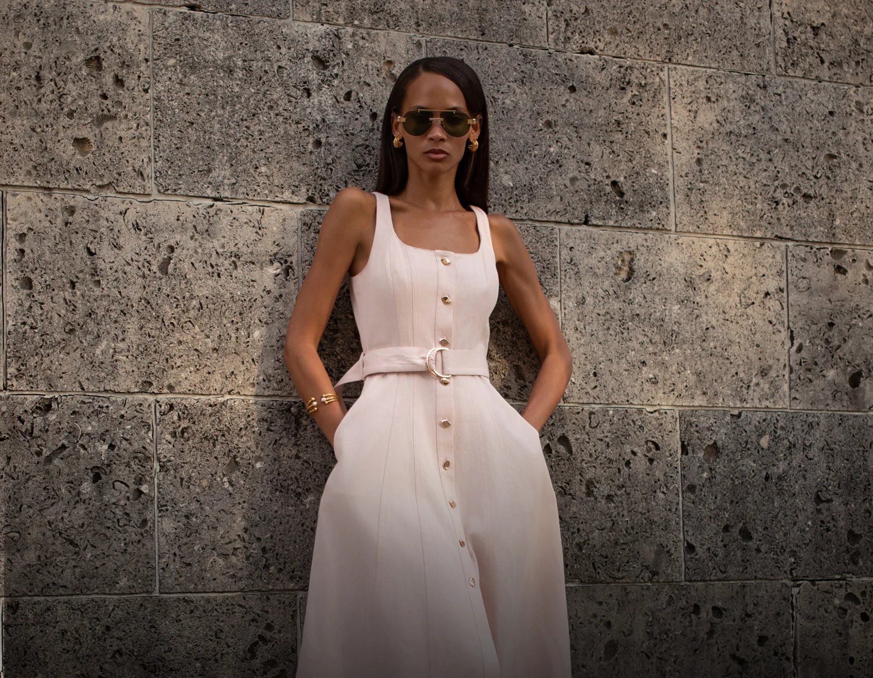 Woman in a white dress standing against a stone wall