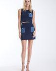 Onyx knit set in navy, cropped sleeveless top and high waisted mini skirt with contrast denim patch pockets, front view on model.