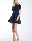 Elsa knit mini dress in navy with a gold button placket and flared skirt, front view on model.