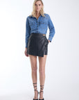 Pauli lambskin leather mini skirt in black with a gold turnlock closure, front view on model.