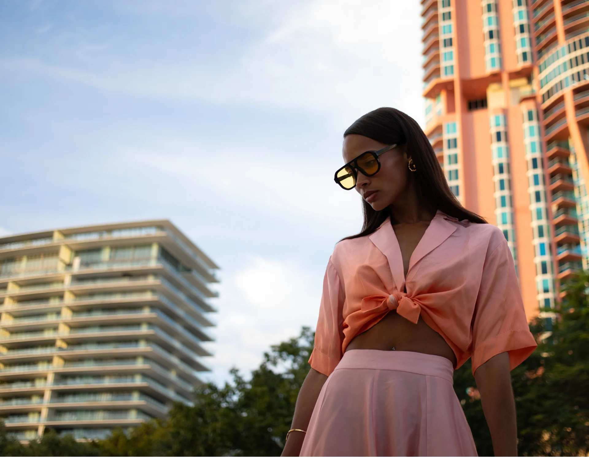 Woman in a pink outfit standing in front of tall buildings