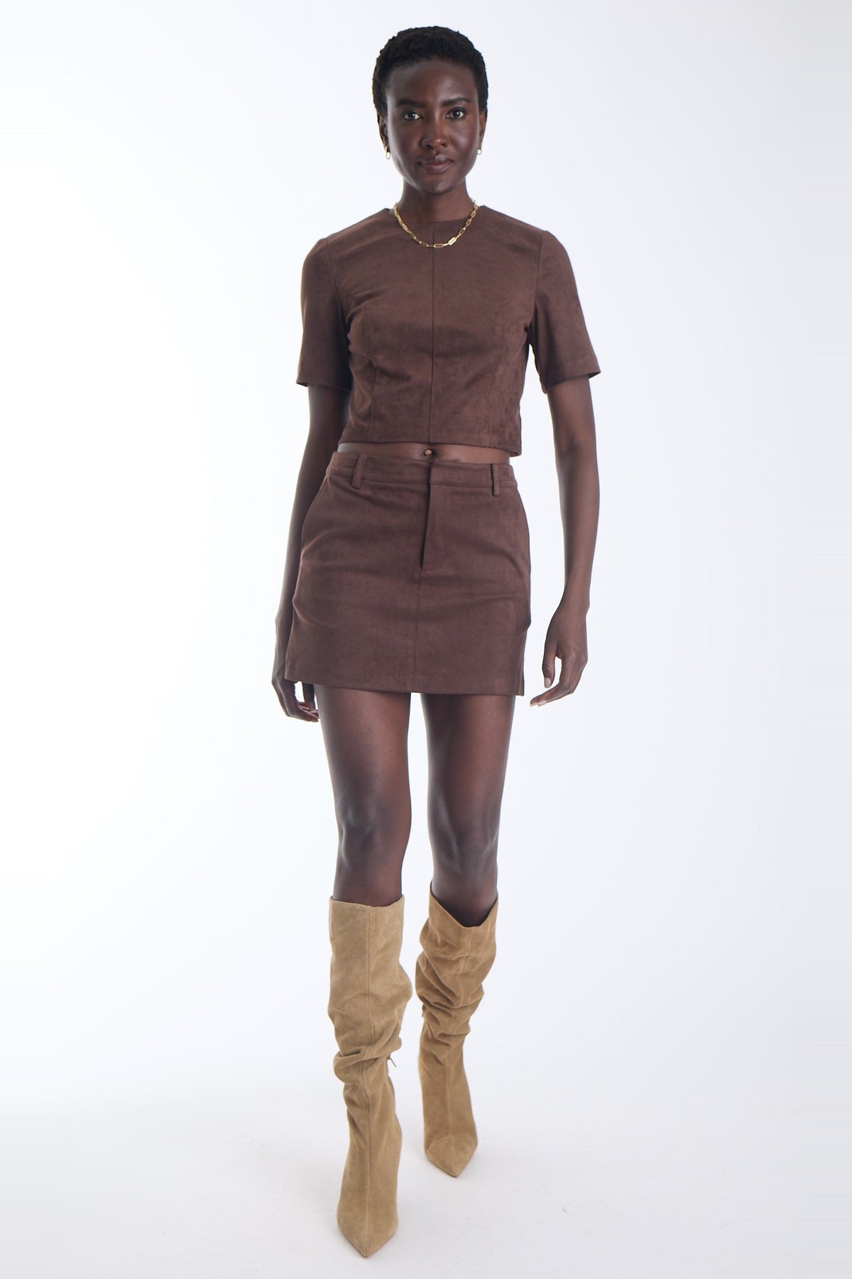 Karina Grimaldi Aria Suede Skirt in chocolate brown, front view on model, mini length with belt loops and a front button