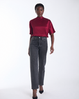 Karina Grimaldi Thea Blouse in mulberry satin, front view on model, high neck with short wide sleeves, worn with jeans