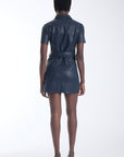 Karina Grimaldi Mallie Vegan Leather Mini Dress in navy, back view on model, short sleeves with the belt tied at the back.