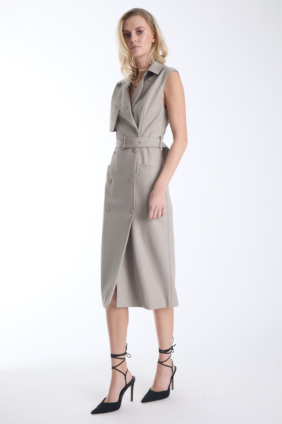 Karina Grimaldi Mila Vegan Leather Trench Dress in stone, front view on model, sleeveless with a collar, double breasted buttons and a wide buckled belt