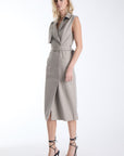 Karina Grimaldi Mila Vegan Leather Trench Dress in stone, front view on model, sleeveless with a collar, double breasted buttons and a wide buckled belt
