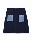 Onyx knit mini skirt in navy showing two contrast denim patch pockets with gold buttons.